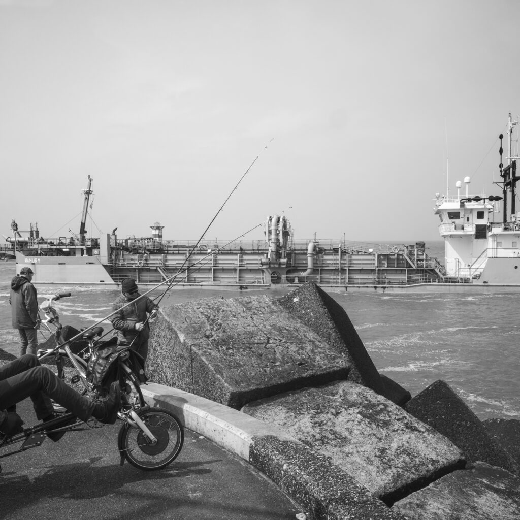 Fisherman standing near shoreline at Noordelijk Havenhoofd strand Scheveningen