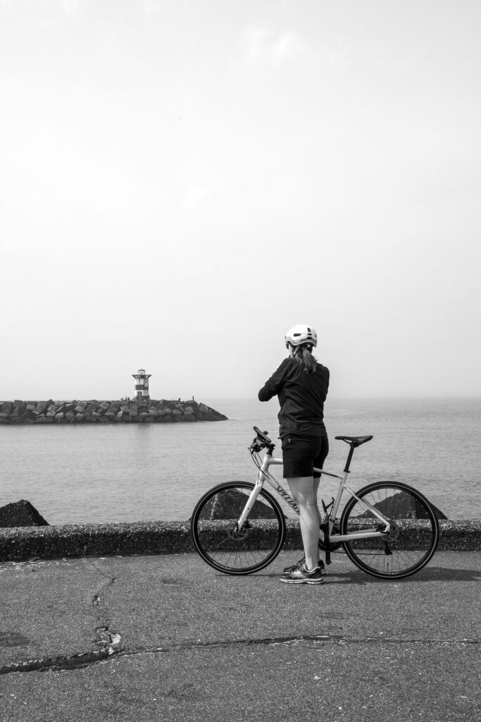 Cyclist riding past red and green harbor lights at Noordelijk Havenhoofd Scheveningen
