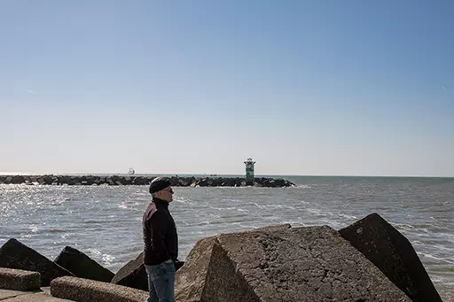 Man standing on concrete blocks at Noordelijk Havenhoofd Scheveningen facing the sea