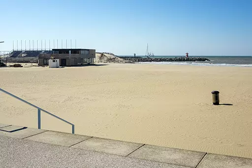 Empty sandy beach and distant harbor entrance at The Hague Beach Stadium, Noorderstrand Scheveningen